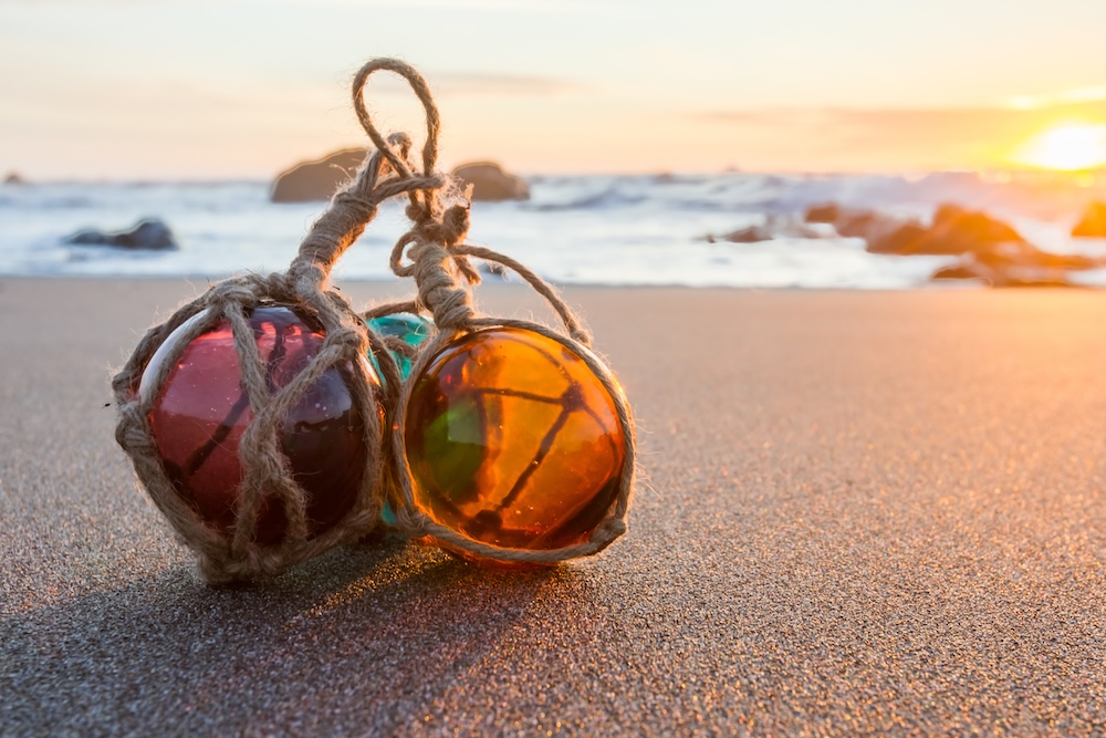 glass floats on beach shore sunset